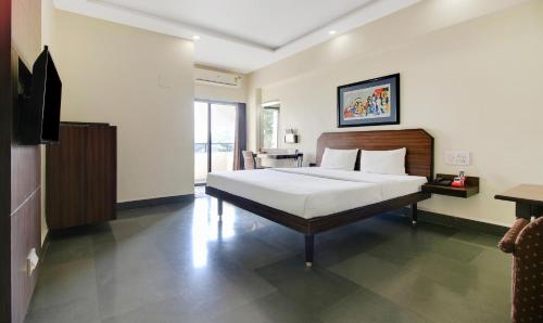 a bedroom with a bed and a television in it at Hotel Hospice in Surat