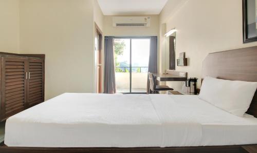 a bedroom with a large white bed and a balcony at Hotel Hospice in Surat