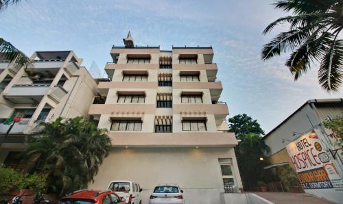a tall building with cars parked in front of it at Hotel Hospice in Surat