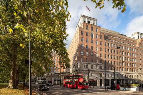 ロンドンにあるGrosvenor House Suitesの市道を走る赤二階バス