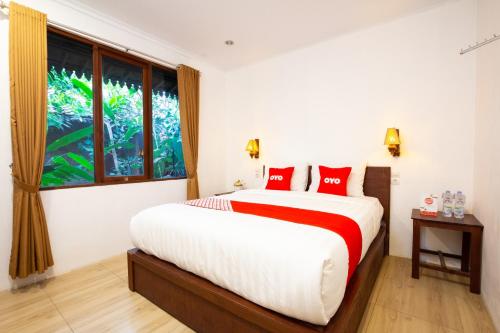 a bedroom with a bed with red pillows and a window at OYO 2068 Abhaya Mudra Homestay in Magelang