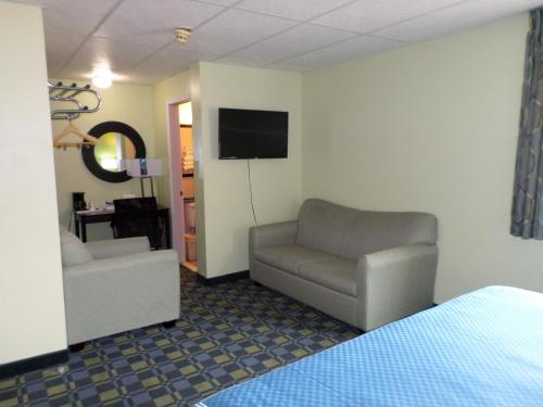 a room with a couch and a chair and a television at Travelodge by Wyndham Cleveland Lakewood in Lakewood