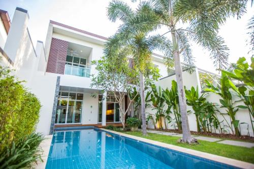 a villa with a swimming pool and palm trees at Two Villas HOLIDAY - Oxygen Style Bangtao Beach, Phuket in Bang Tao Beach