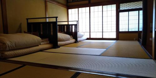 a room with mats on the floor in a room with windows at K's House Ito Onsen - Historical Ryokan Hostel in Ito