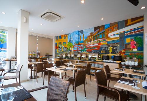 明古魯的住宿－Cordela Inn Bengkulu，餐厅设有桌椅,墙上挂有绘画作品
