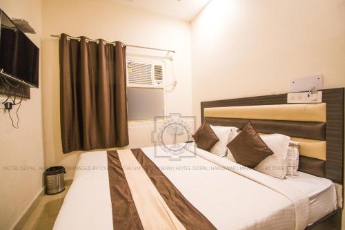 - une chambre avec un lit doté de draps blancs et une fenêtre dans l'établissement Hotel Gopal, à Haridwar