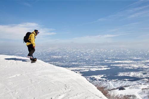 a man riding a snowboard on top of a snow covered mountain at Lotte Arai Resort in Myoko
