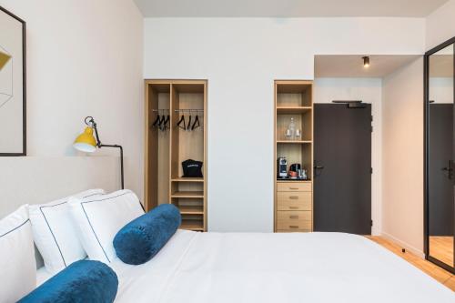 a bedroom with a white bed with blue pillows at Le Grand Quartier in Paris