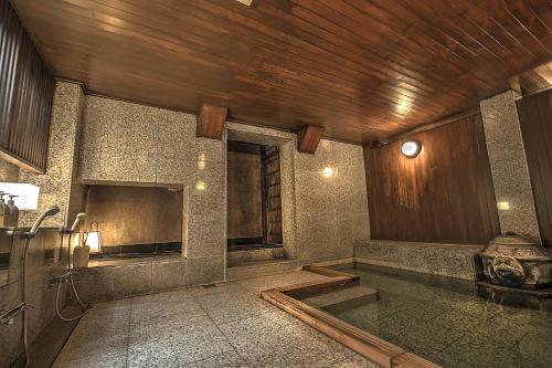baño con bañera y techo de madera en K's House Ito Onsen - Historical Ryokan Hostel, en Ito