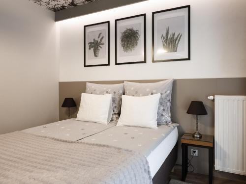 a bedroom with a bed with four pictures on the wall at Jacuzzi Apartments in Kraków