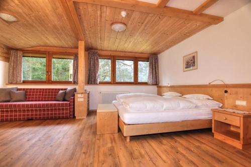 a bedroom with a large bed and a couch at Hotel Resa Blancia in San Vigilio Di Marebbe