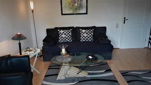 ein Wohnzimmer mit einem schwarzen Sofa und einem Glastisch in der Unterkunft Ferienwohnung Gossel in Bad Wildungen