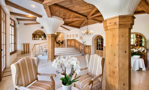 a living room with wooden ceilings and chairs and a staircase at Hotel Spitaler in Appiano sulla Strada del Vino