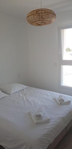 ein Schlafzimmer mit einem weißen Bett mit Handtüchern darauf in der Unterkunft Les TERRASSES de BELLA VISTA(b) Belle maison bord de mer in Saint-Vincent-sur-Jard