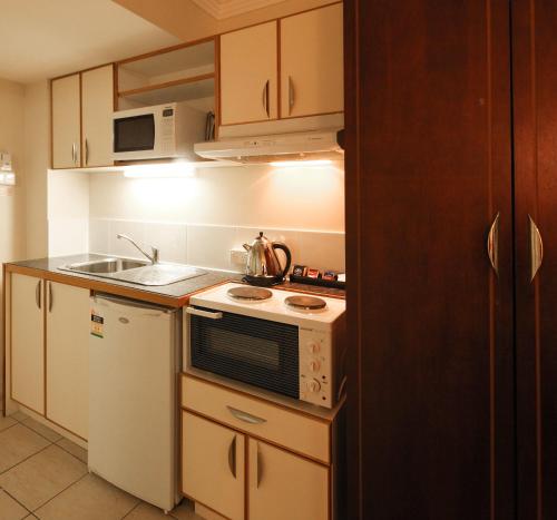 a kitchen with a stove, sink, microwave and refrigerator at Best Western Astor Metropole in Brisbane