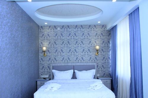 - une chambre avec un lit doté de draps blancs et d'un plafond dans l'établissement Flamenco Hotel, à Sisian