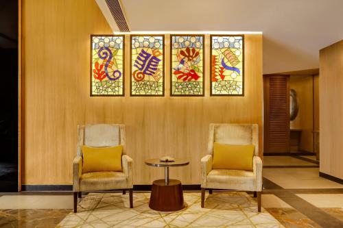 two chairs and a table in a lobby with stained glass at Lemon Tree Hotel Viman Nagar Pune in Pune