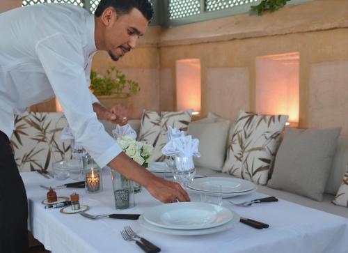 un hombre parado sobre una mesa con platos en ella en Dar Housnia, en Marrakech