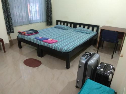a bedroom with a bed with luggage and a table at Cozy Living in Guwahati