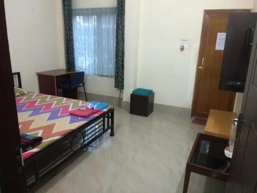 a bedroom with a bed and a desk and a television at Cozy Living in Guwahati