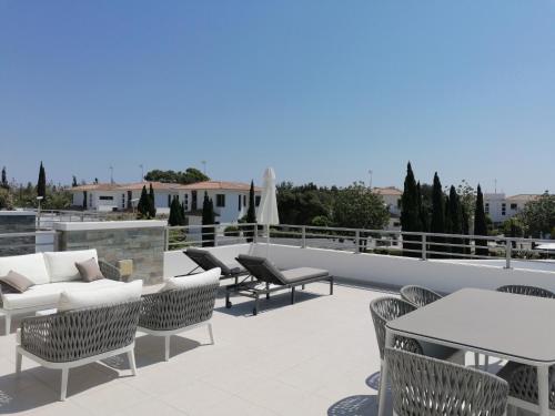a patio with chairs and tables on a roof at Atlantis Gardens in Mazotos