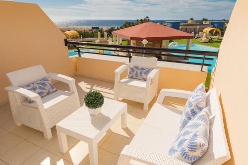 un balcón con sillas y mesas y una piscina en Palm Garden Jandía By CanariasGetaway, en Morro del Jable