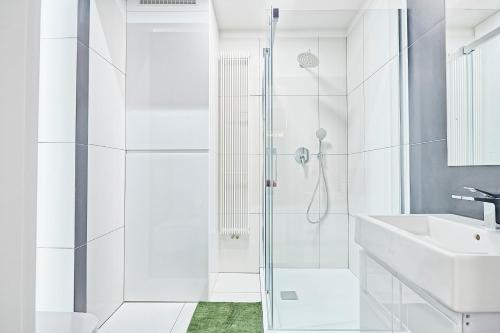 a white bathroom with a shower and a sink at Krupnicza Premium Apartments in Krakow