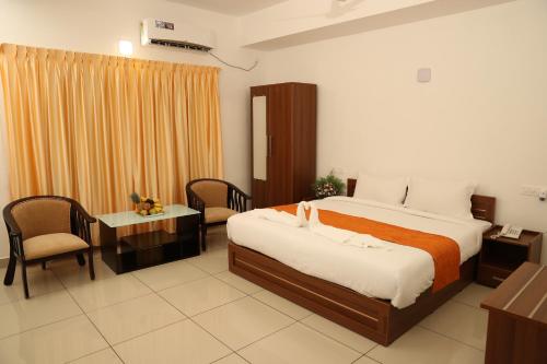 a hotel room with a bed and a desk and chair at Sunstar Residency & Food Plaza Pala in Lālam