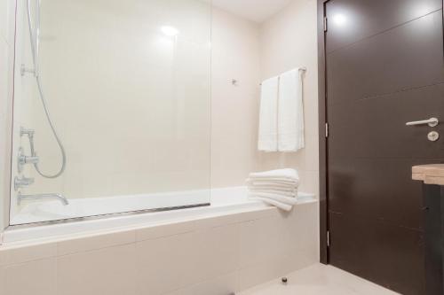 a bathroom with a shower and a tub and a sink at Quintessential Quarters - Burj Khalifa and Sea Views in Dubai