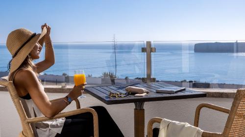 a woman sitting at a table with a glass of orange juice at Pousada de Sagres in Sagres
