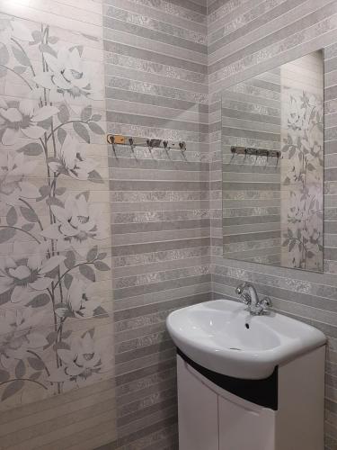 a bathroom with a sink and flowers on the wall at Paradise Guest House in Tsaghkadzor