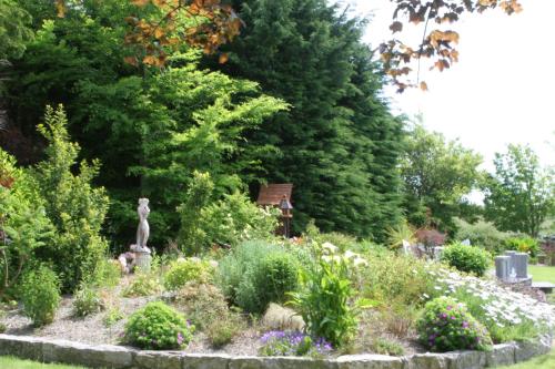 a garden with flowers and a statue in the middle at Friars Quarter House in Ballinrobe