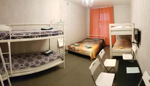a room with three bunk beds and a table and chairs at Hotel Pastel on Vosstaniya in Saint Petersburg