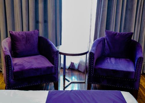 two purple chairs and a table in a room at Indigo Heights Hotel & Suites in Lahore