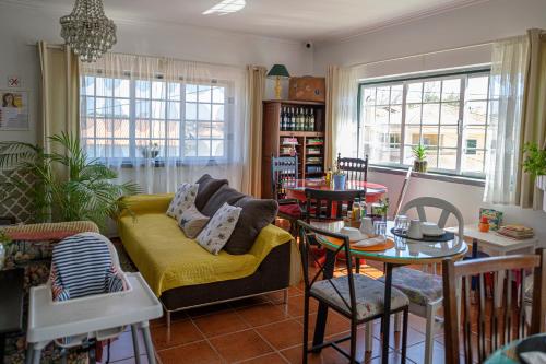 uma sala de estar com um sofá amarelo e mesas em Casa das Hortênsias - Charming Guest House em Sintra