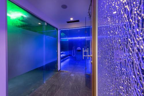 baño con ducha con luces moradas y verdes en Hotel Puint, en Ladis