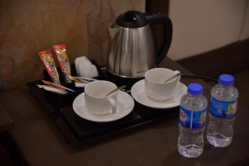 ein Tablett mit zwei Tassen und zwei Flaschen Wasser in der Unterkunft Prizh Hotel in Sulaimaniyya
