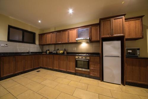 uma grande cozinha com armários de madeira e um frigorífico em Bukoto Heights Apartments em Kampala