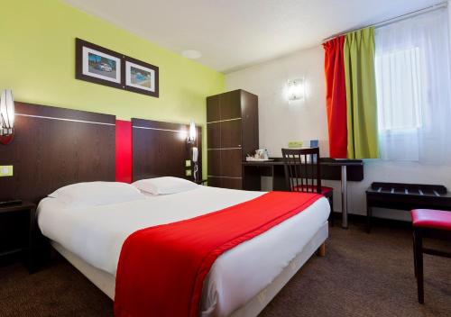 a hotel room with a large bed and a desk at Enzo Hotels Reims Tinqueux by Kyriad Direct in Reims