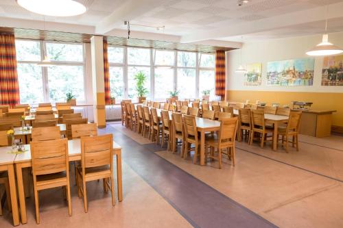 a dining room with tables and chairs and windows at Jugendherberge Flensburg in Flensburg