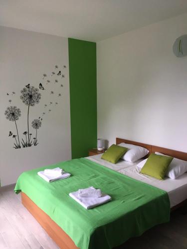 a green bedroom with two beds with towels on them at House Matusko in Saplunara