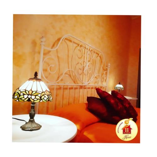 a bed with red pillows and a lamp on a table at La Casa di Ninna Affittacamere in Ariano Irpino