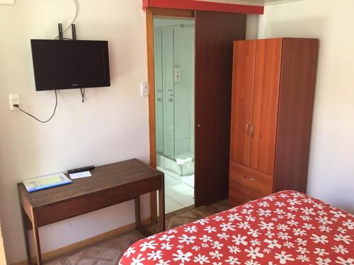 a bedroom with a bed and a table and a television at Eco Hostal Offenbacher-Hof in Viña del Mar