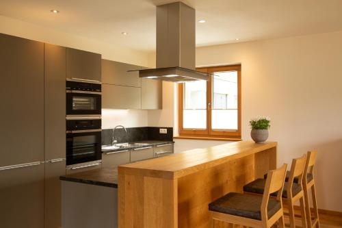 a kitchen with a wooden counter with chairs in it at Romantik Chalet im Weingut Eichenstein in Merano