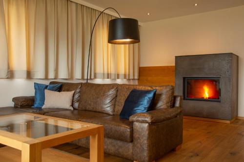 a living room with a brown couch and a fireplace at Romantik Chalet im Weingut Eichenstein in Merano