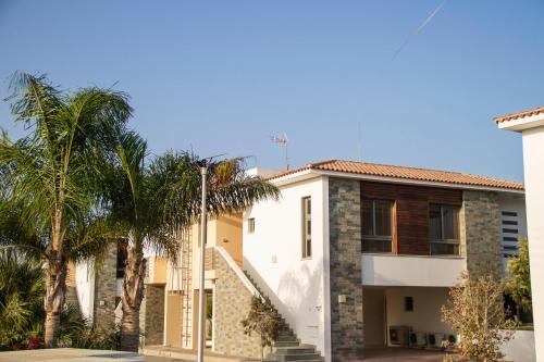 a house with palm trees in front of it at Atlantis Gardens in Mazotos