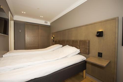 - une chambre avec un grand lit et une tête de lit en bois dans l'établissement Dr. Holms Hotel Leilighet, à Geilo