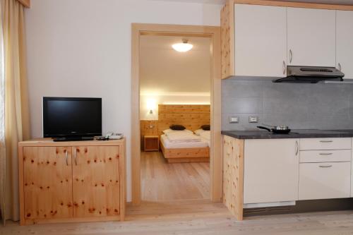 a kitchen with a tv on a counter and a room at Christophorus Mountain Residence in San Vigilio Di Marebbe
