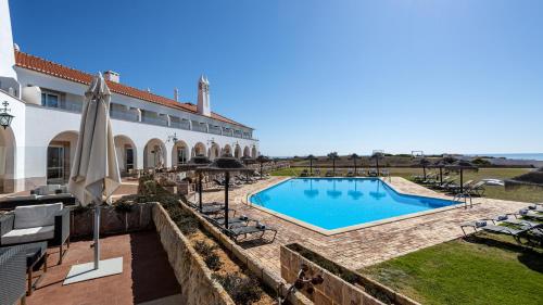 a villa with a swimming pool in front of a building at Pousada de Sagres in Sagres