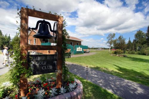 a bell in a garden with a sign and flowers at Deer Lake Horizon Hotel in Deer Lake